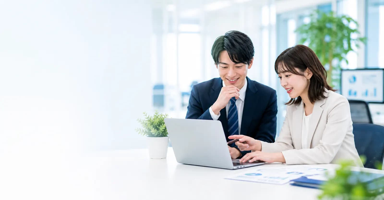 オフィスでノートパソコンを見ながら請求業務について打ち合わせる社員
